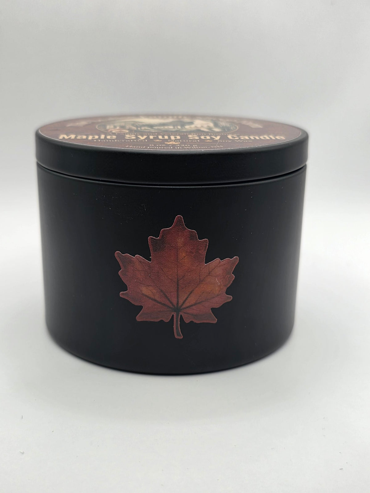 Side view of the black Maple Syrup Soy Candle tin with maple leaf